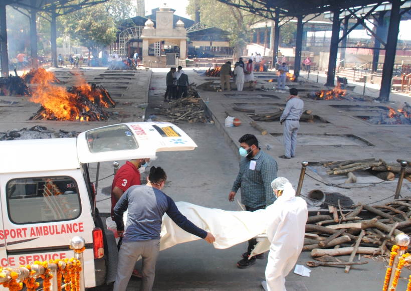 स्वास्थ्य कार्यकर्ता और रिश्तेदार अंतिम संस्कार के लिए कोविड -19 प्रभावित पीड़ितों के शव को ले जाते