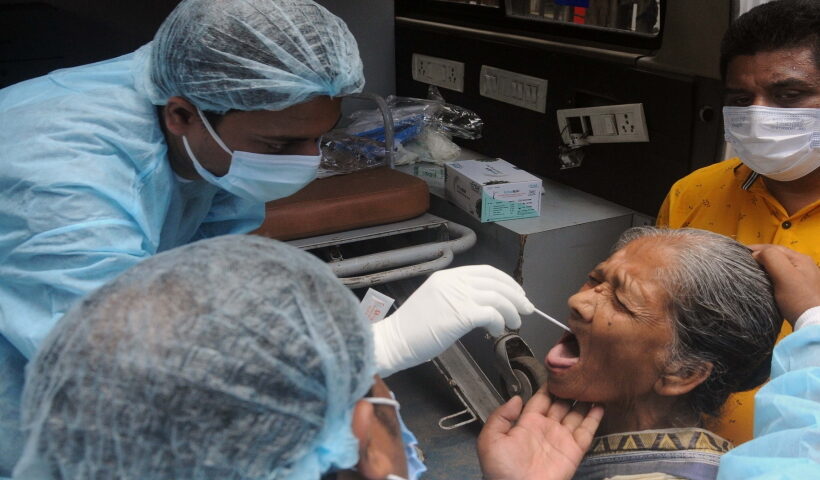 A health worker collects a swab sample from an elderly woman for Covid-19