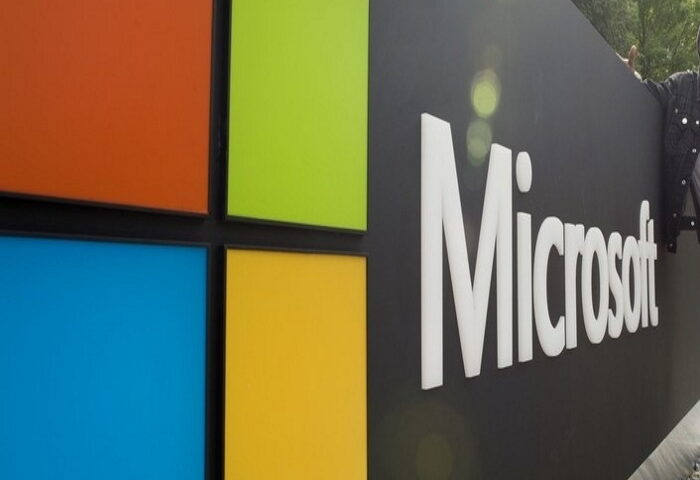 A visitor poses for a photo with Microsoft's logo at Microsoft's corporate headquarters in Redmond, Washington