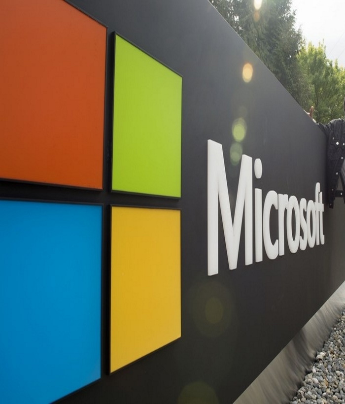 A visitor poses for a photo with Microsoft's logo at Microsoft's corporate headquarters in Redmond, Washington