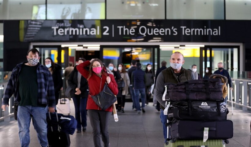 A passenger walks past a public health notice in Heathrow Airport in London, Britain