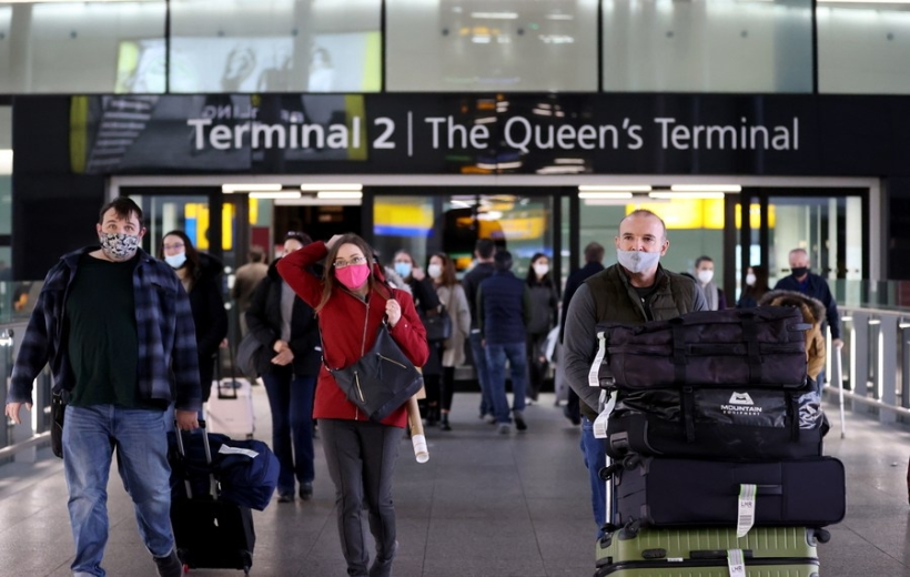 A passenger walks past a public health notice in Heathrow Airport in London, Britain