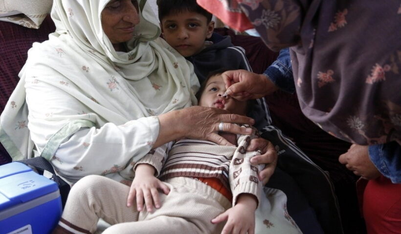 A female health worker administrates polio-vaccine drops to a child during a door-to-door health service camping on the outskirts of Islamabad,