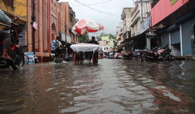 Meerut: Commuters wade through a waterlogged road during rain in Meerut