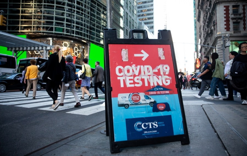 Pedestrians pass a sign advertising a COVID-19 testing site in New York, the United States,