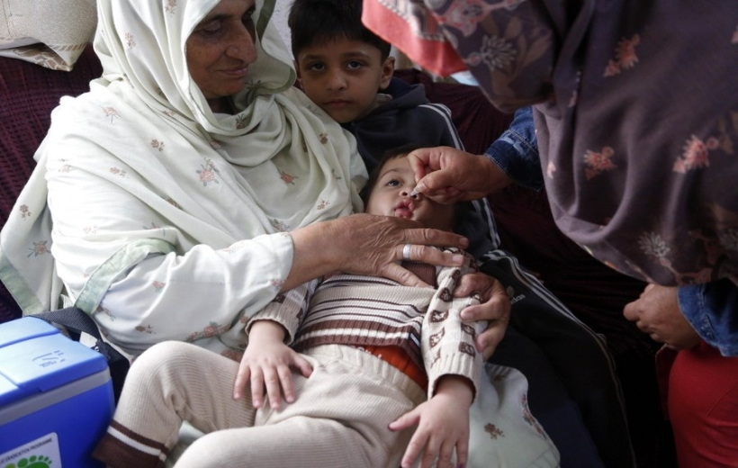 A female health worker administrates polio-vaccine drops to a child during a door-to-door health service camping on the outskirts of Islamabad, capital of Pakistan
