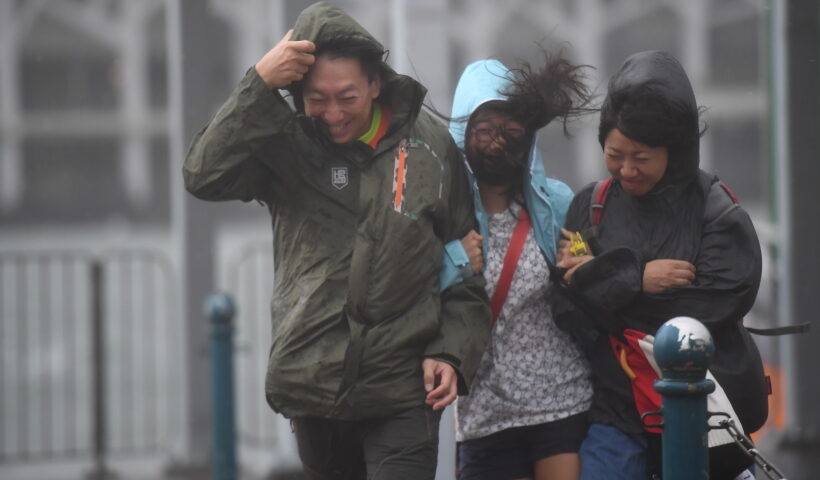 Citizens walk against wind in Hong Kong, south China, Aug. 23, 2017. Hato, the 13th typhoon this year, landed at noon Wednesday in Zhuhai City, south