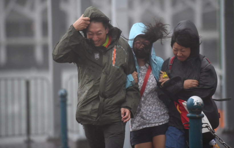 Citizens walk against wind in Hong Kong, south China, Aug. 23, 2017. Hato, the 13th typhoon this year, landed at noon Wednesday in Zhuhai City, south