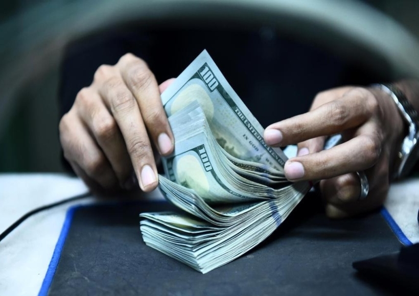 A teller counts U.S. dollar banknotes in Karachi, southern Pakistan,
