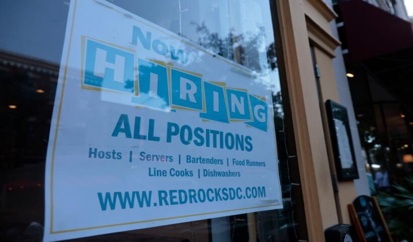 A hiring sign is posted on the window of a restaurant in the Old Town neighborhood of Alexandria