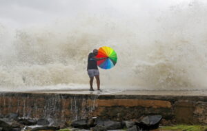 Chennai: A man holding an umbrella tries to protect himself from sea waves due to the landfall of cyclone storm Mandous, in Chenna