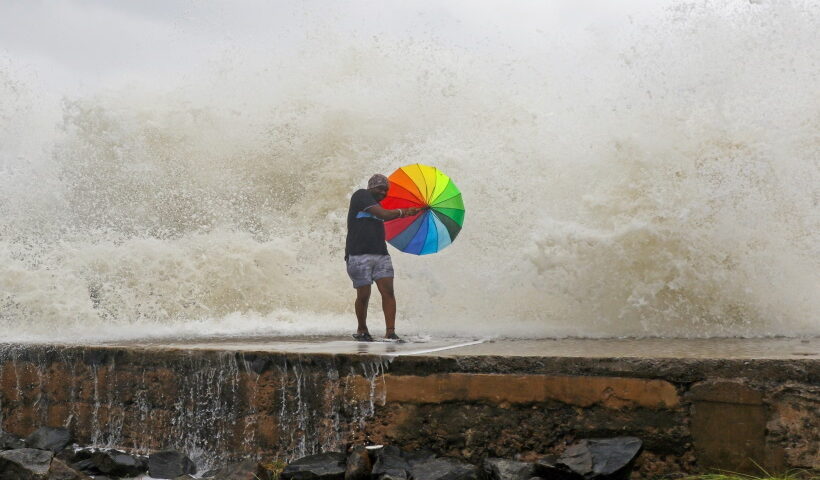Chennai: A man holding an umbrella tries to protect himself from sea waves due to the landfall of cyclone storm Mandous, in Chenna