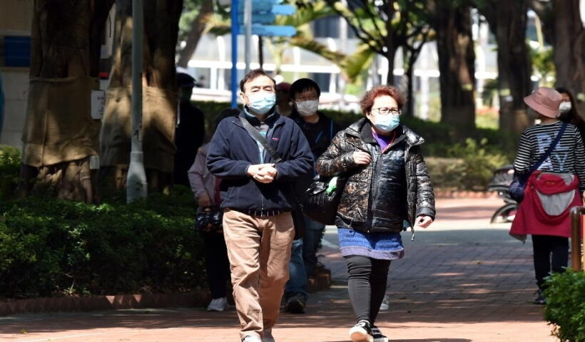 People wearing masks walk on road in Hong Kong