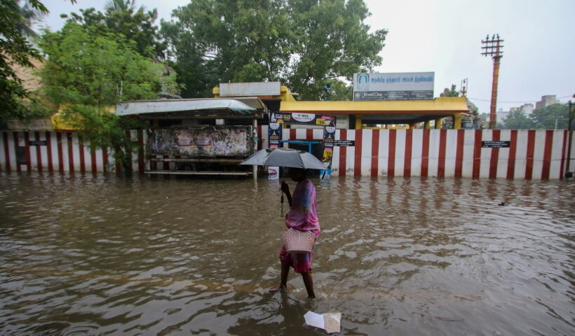 Chennai: A woman holding an umbrella wades through a waterlogged road after heavy rain, in Chennai on Friday,