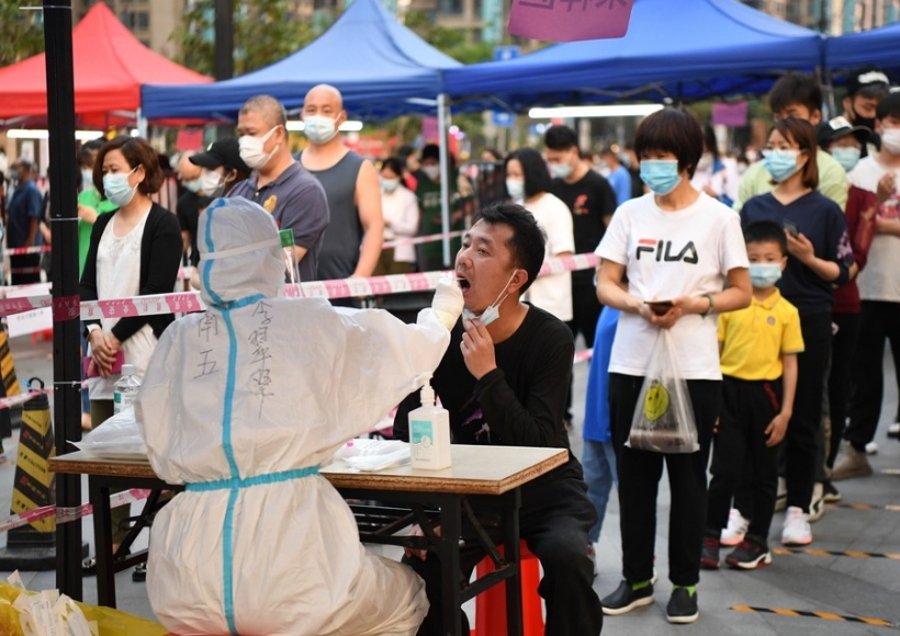 A medical worker takes a swab sample from a resident for nucleic acid test at a community in Liwan District of Guangzhou