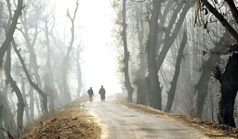 Srinagar: People walk past on a road during dense fog on a cold morning in Srinagar on Sunday,