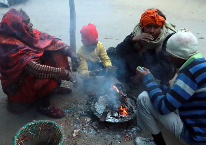 People keep themselves warm around a bonfire on a cold winter day