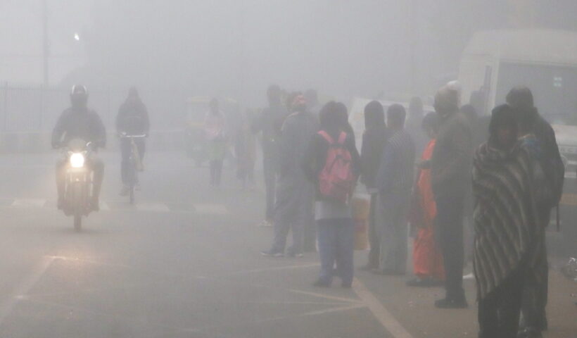 New Delhi: People stand on a road waiting for a bus as the thick layer of fog engulfs on a cold morning, in New Delhi