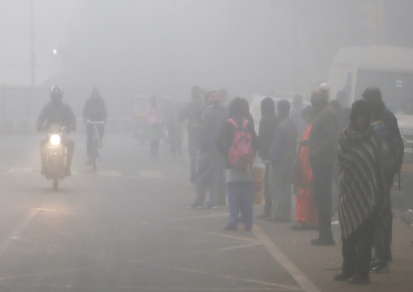 New Delhi: People stand on a road waiting for a bus as the thick layer of fog engulfs on a cold morning, in New Delhi
