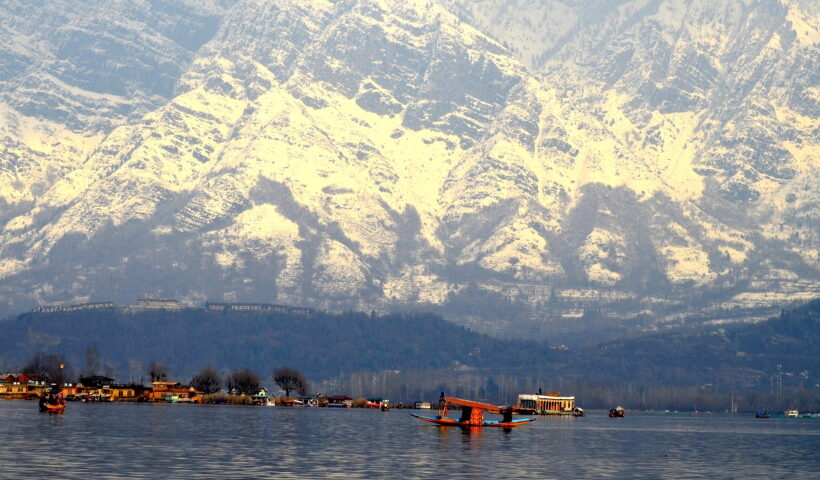 Srinagar: A boatman rows his shikara in Dal Lake as the mountains are covered with snow in Srinagar