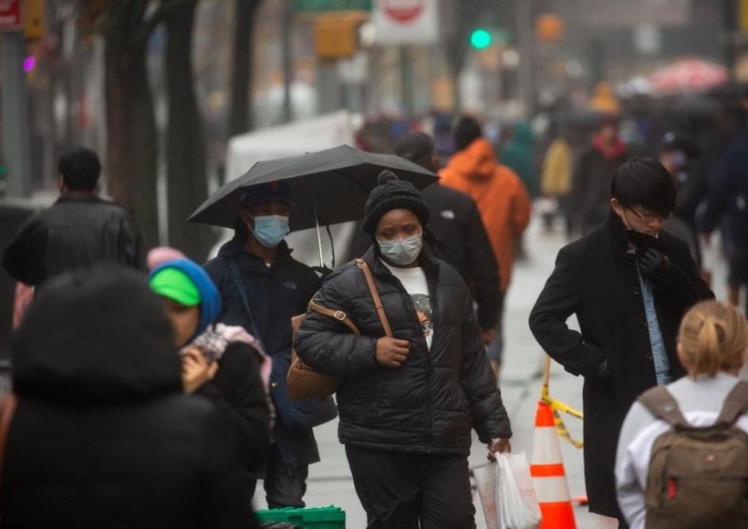 People wearing face masks walk along Fulton Street in New York, the United States,