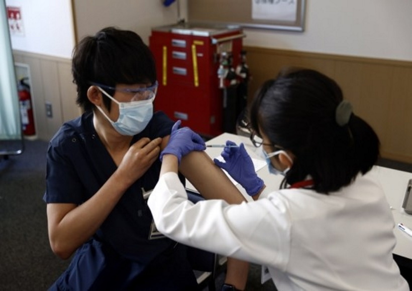 A medical worker receives a dose of the COVID-19 vaccine as the country launches its inoculation campaign at the Tokyo Medical