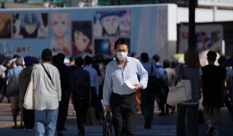 People wearing face masks walk on a street in Tokyo, Japan