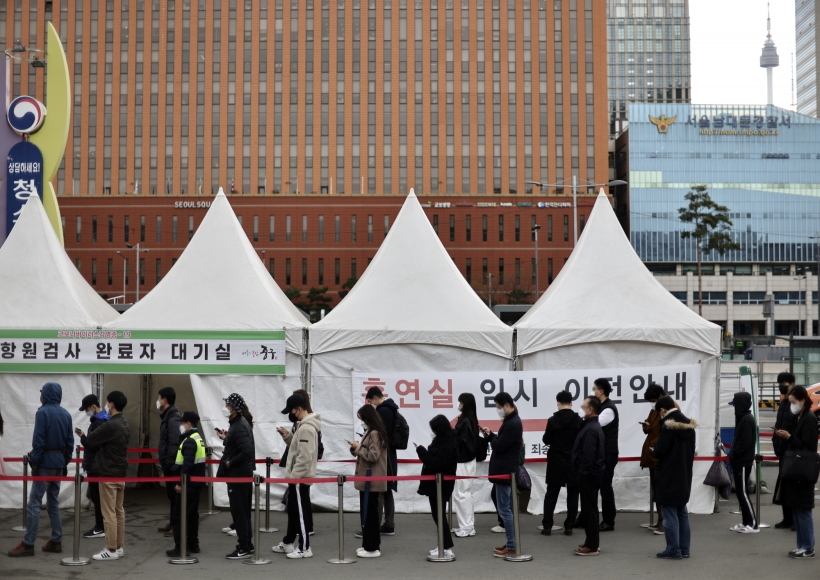 People stand in line to take coronavirus tests at a screening clinic in front of Seoul Station on March 31, 2022. South Korea's new daily COVID-19 cases fell more than 100,000 to around 320,000, but the number of seriously ill patients hit an all-time high amid the continued spread of the highly transmissible "stealth omicron" subvariant