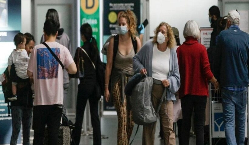 Travelers with face masks are seen at Vancouver International Airport in Richmond, Canada,