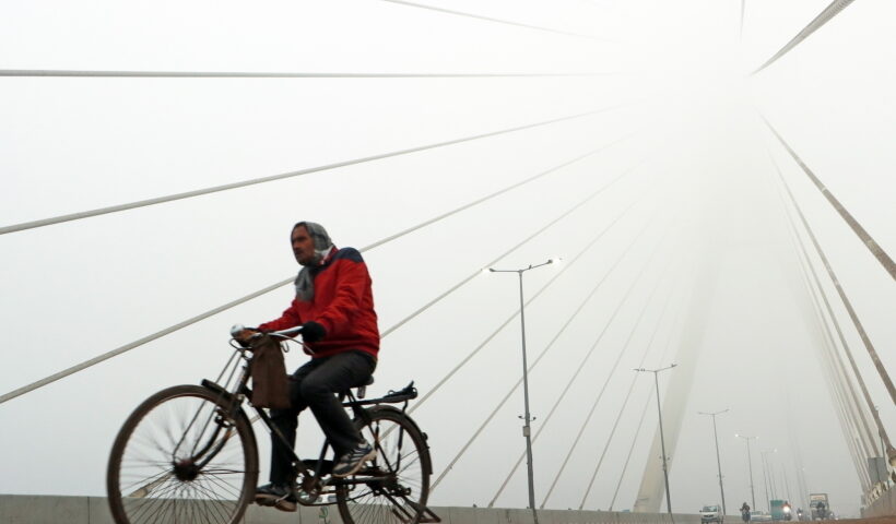 New Delhi: A man paddles the cycle as he passes through Signature bridge on a cold and foggy morning in New Delhi