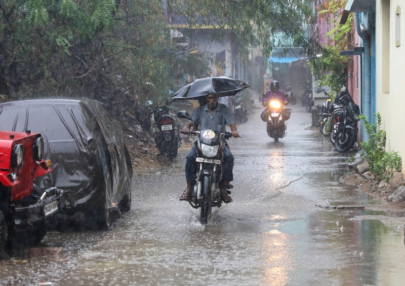 Chennai: A man on a motorbike holds an umbrella ride past during heavy rain in Chennai
