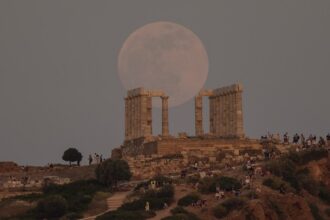 A full moon in the sky over the ancient Temple of Poseidon at Cape Sounion