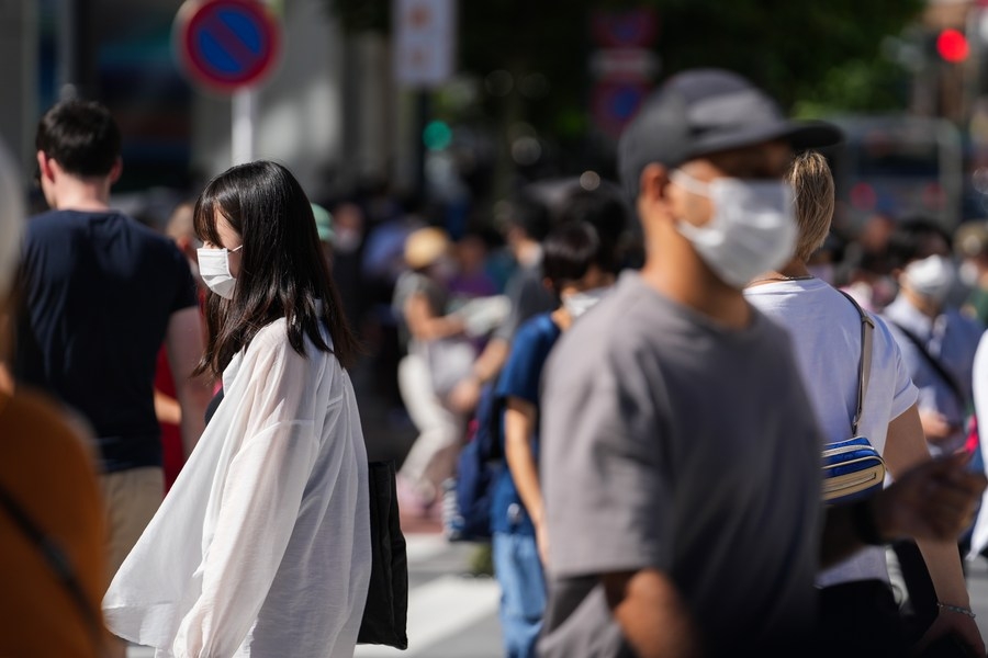 People wearing face masks walk on a street in Tokyo