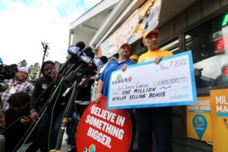 Business owner Joe Chahayed (1st R) holds a Powerball bonus check outside Joe's Service Center that sold the winning Powerball ticket of 2.04 billion U.S. dollars in Altadena, California, the United States