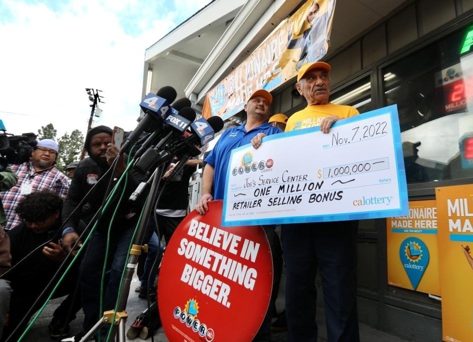 Business owner Joe Chahayed (1st R) holds a Powerball bonus check outside Joe's Service Center that sold the winning Powerball ticket of 2.04 billion U.S. dollars in Altadena, California, the United States