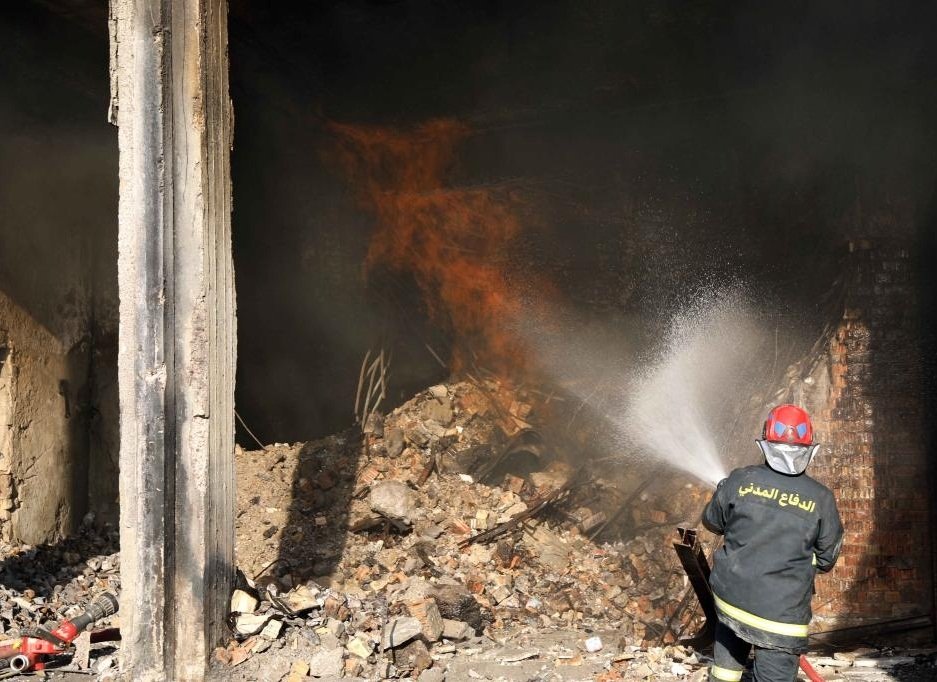 A rescuer battles a building fire in central Baghdad