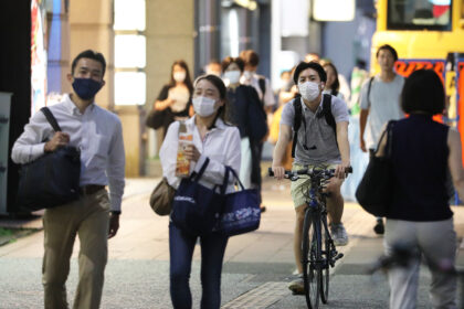 People wearing face masks walk on the street in Tokyo