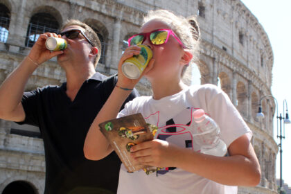 Tourists drink under the sun in front of the Colosseum