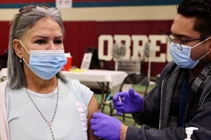 A health worker administers a flu vaccine shot to a local resident in Los Angeles