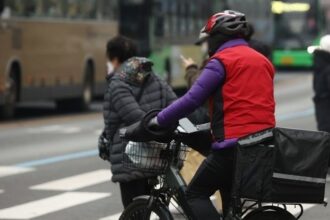 A delivery worker crosses a street in Seoul