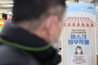 A man walks past a sign asking visitors to wear masks