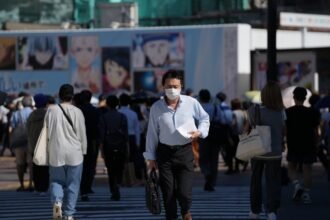 People wearing face masks walk on a street in Tokyo