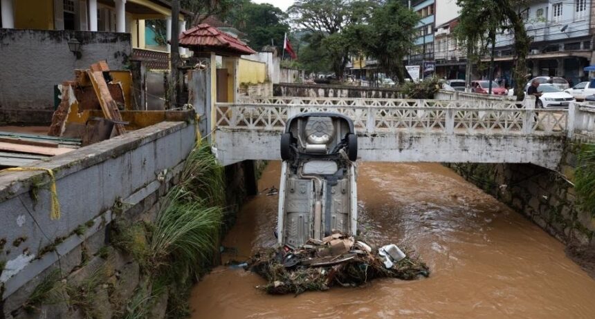 Damaged trees and vehicles block a road after heavy rains