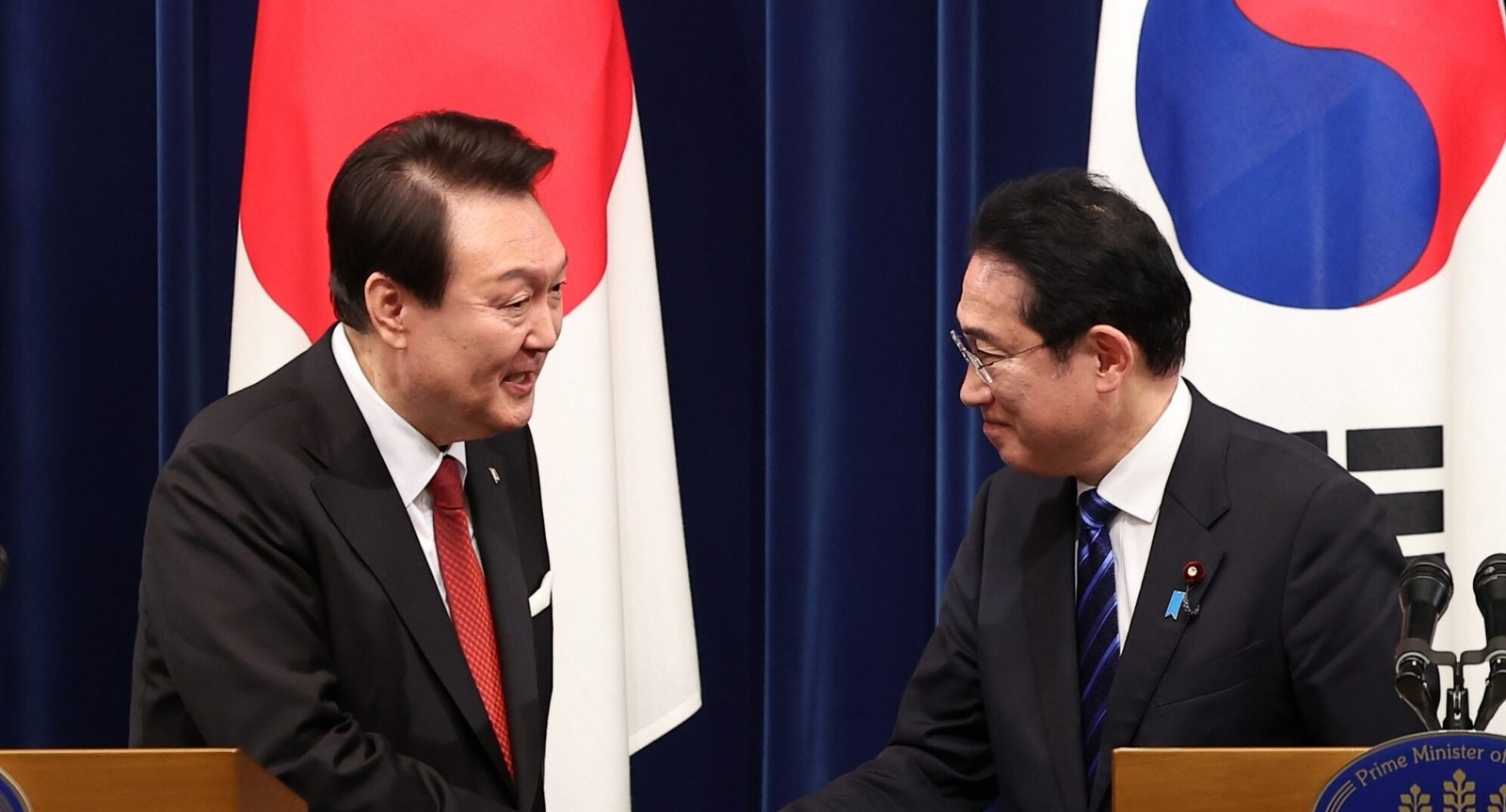 President Yoon Suk Yeol (L) shakes hands with Japanese Prime Minister Fumio Kishida