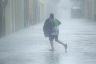 A man walks in the rain on a road