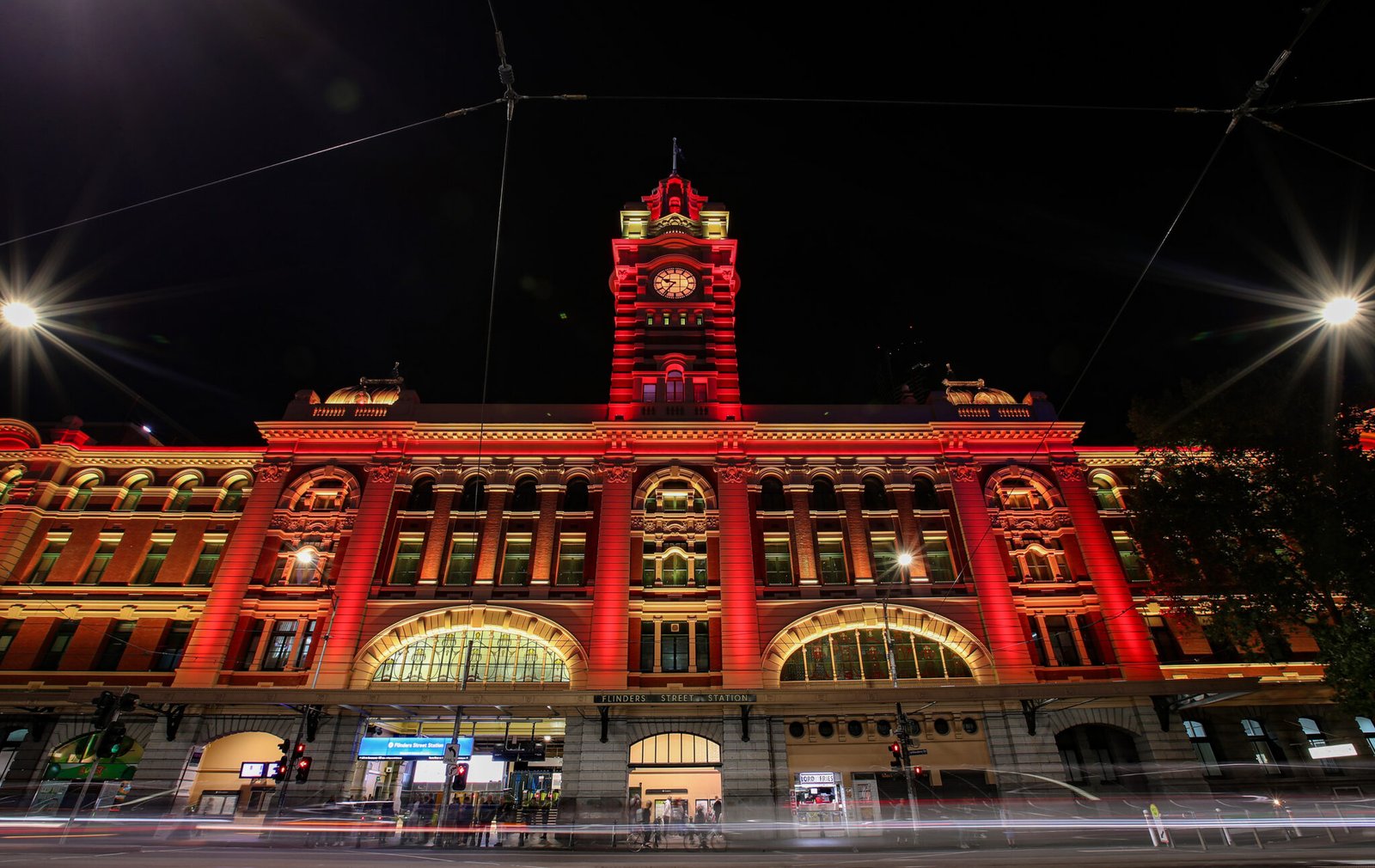 Flinders Street Station is lit up in red in Melbourne