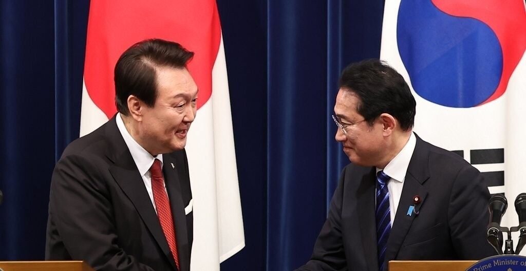 President Yoon Suk Yeol (L) shakes hands with Japanese Prime Minister Fumio Kishida