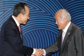 Finance Minister Choo Kyung-ho (L) shakes hands with his Japanese counterpart, Shunichi Suzuki
