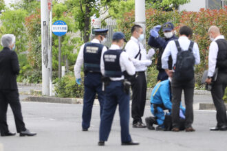 Police officers investigate around the stabbing