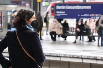 A woman wearing a face mask waits for a train in Berlin